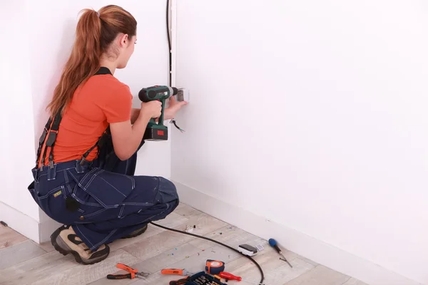 Woman drilling hole in wall — Stock Photo, Image