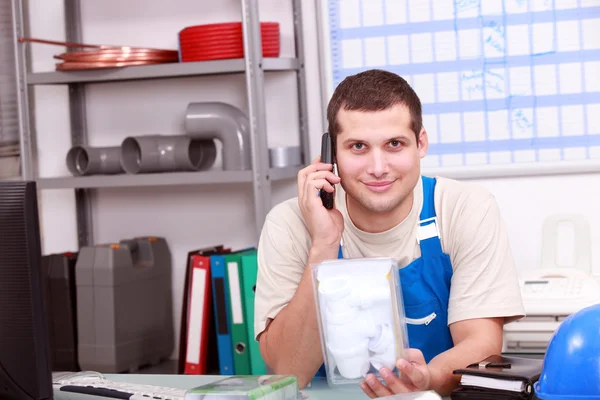 Man on telephone checking a plumbing part — Stock Photo, Image