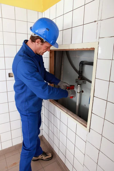 Loodgieter werken in een betegelde kamer — Stockfoto