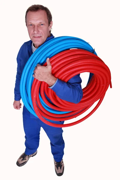 Studio shot of plumber with reels of tube — Stock Photo, Image