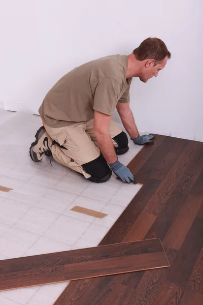 Homem que estabelece piso laminado — Fotografia de Stock