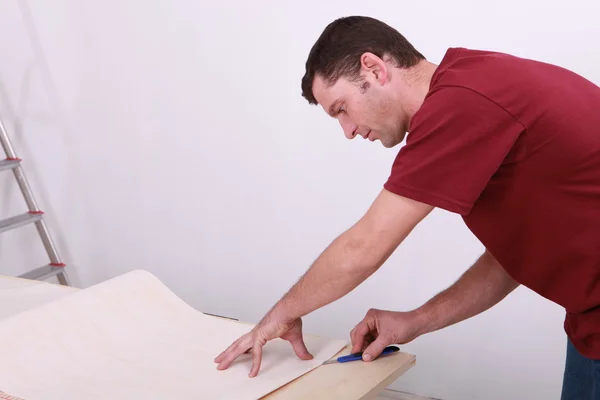 Tradesman cutting a sheet of paper — Stock Photo, Image