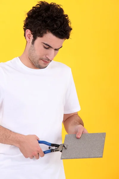Young tiler at work against yellow studio background — Stock Photo, Image