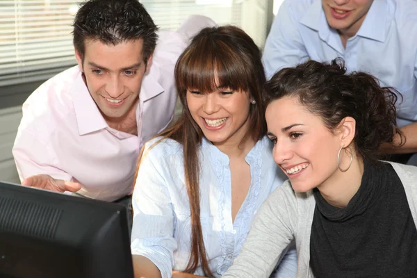 Office workers laughing in front of computer — Stock Photo, Image