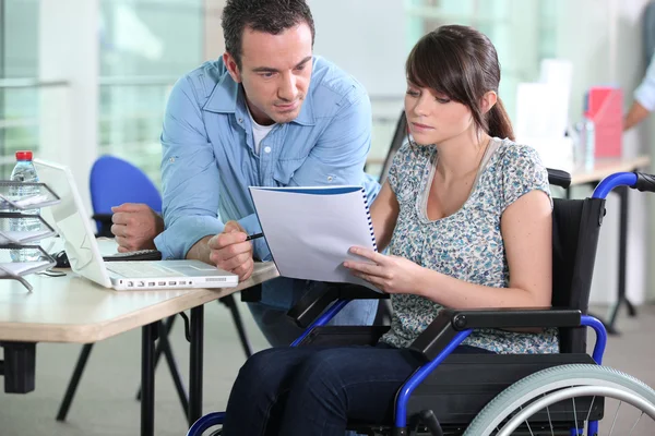 Молодая женщина в инвалидной коляске работает с коллегой-мужчиной — стоковое фото