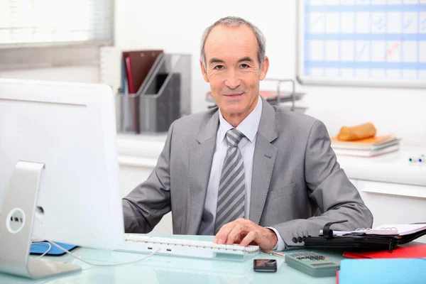 Senior zakenman werkt op een computer — Stockfoto