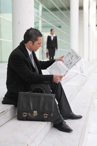 Homme d'affaires lisant un journal devant un immeuble de bureaux — Photo