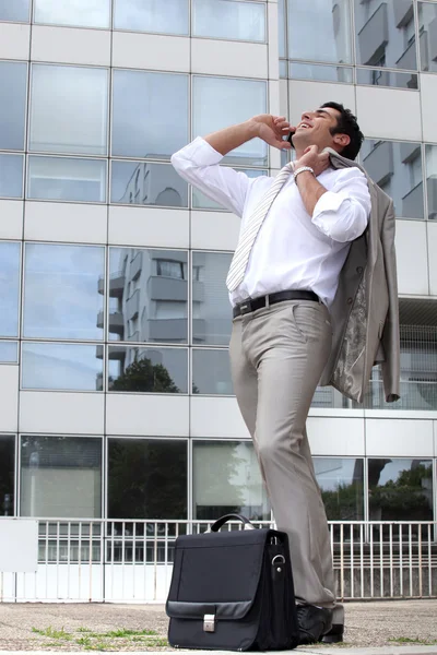 Biznesmen śmiechem na jego telefon poza budynek biurowy — Zdjęcie stockowe