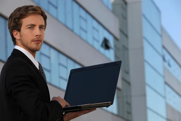 Jovem empresário usando um laptop com uma tela em branco — Fotografia de Stock