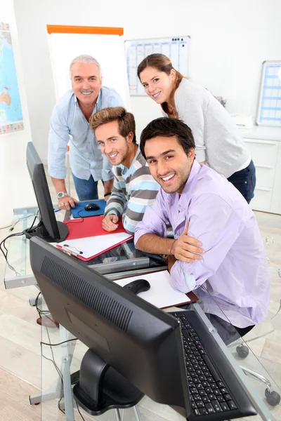 Négy mosolyogva összegyűjtött kerek egy számítógép, egy osztályteremben — Stock Fotó