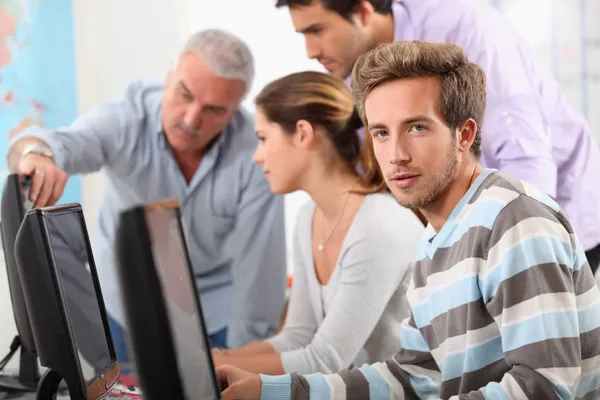 Profesor y estudiantes reunidos alrededor de la pantalla del ordenador —  Fotos de Stock