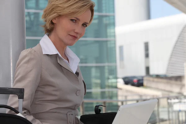 Zakenvrouw op laptop buiten luchthaven — Stockfoto