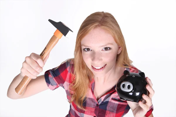 Grappig schot van jonge meisje proberen in te breken open haar piggy bank met een hamme — Stockfoto