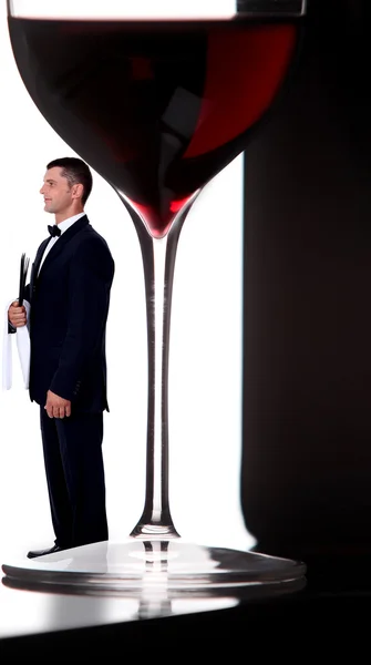 Vinho mordomo posando ao lado de um copo gigante de vinho — Fotografia de Stock