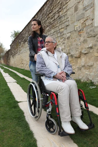 Νεαρή γυναίκα με την ηλικιωμένη γυναίκα σε αναπηρική καρέκλα — Φωτογραφία Αρχείου