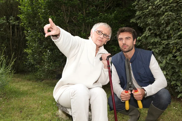 Young man and older woman in garden — Stock Photo, Image