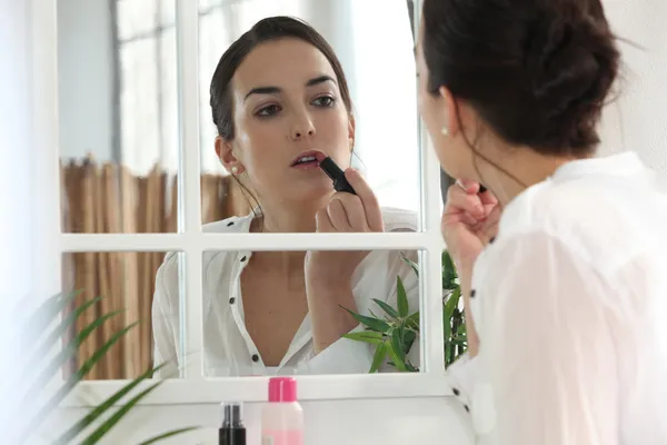 Femme appliquant le visage de rouge à lèvres sur le miroir — Photo
