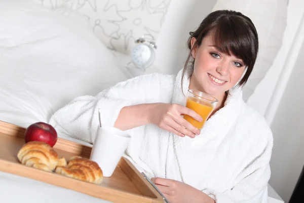 Fröhliches Mädchen frühstückt im Bett — Stockfoto