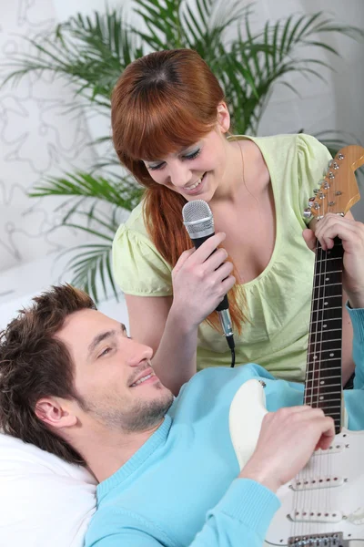Νεαρό ζευγάρι με μια κιθάρα και ένα μικρόφωνο — Φωτογραφία Αρχείου