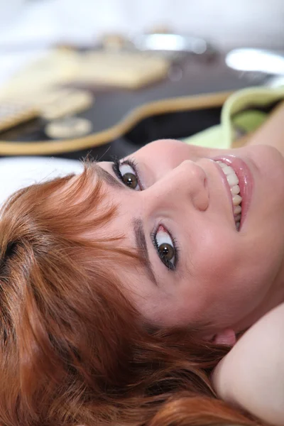 Kobieta, leżąc na łóżku z gitarą — Zdjęcie stockowe