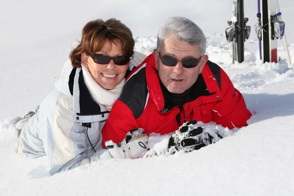 Старшая пара, лежащая в снегу — стоковое фото
