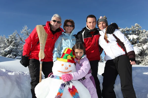Familia con un muñeco de nieve — Foto de Stock