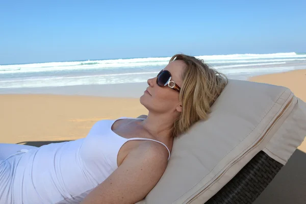 Frau entspannt sich auf einer Liege am Strand — Stockfoto