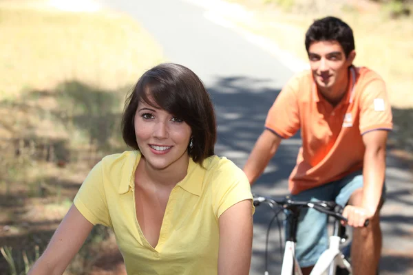 Giovane coppia in sella alle bici in campagna — Foto Stock
