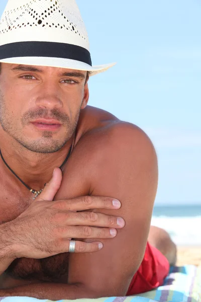 Acercamiento de un hombre en un sombrero de paja acostado en la playa — Foto de Stock