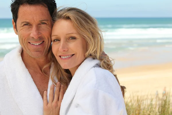 Couple stood by the sea wearing bathrobes Royalty Free Stock Photos