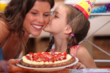 Daughter kissing mommy at birthday party clipart