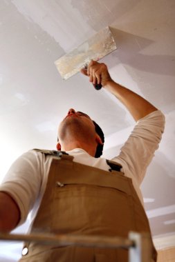 Man putting up a plasterboard ceiling clipart