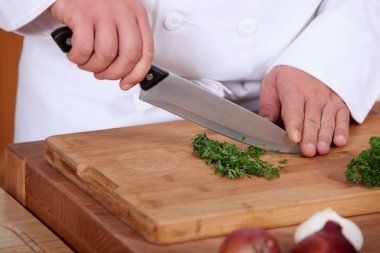 Hands of cook cutting parsley clipart