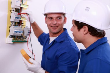 Electrical safety inspectors verifying central fuse box clipart