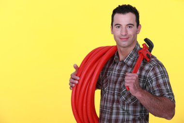 Tradesman holding corrugated tubing and a pipe wrench clipart