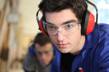 Closeup of a young worker wearing ear defenders clipart