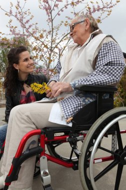 Young woman with an elderly lady in a wheelchair clipart