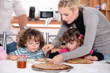 Parents preparing breakfast for children clipart