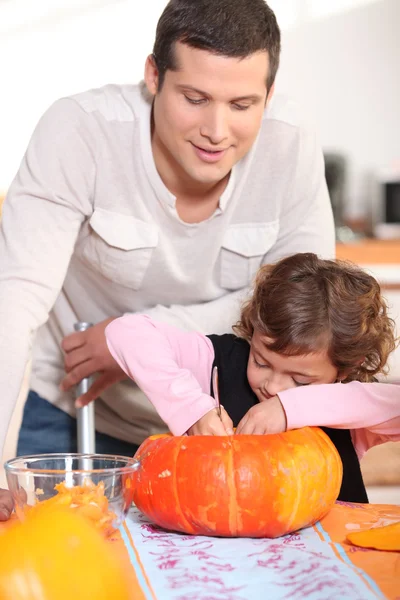 Otec a jeho dcera řezbářské pumpkins v kuchyni — Stock fotografie