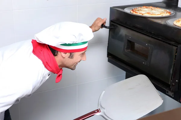 Cook watching pizzas in oven — Stock Photo, Image