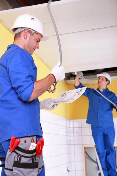 Eletricistas instalando cabeamento elétrico — Fotografia de Stock