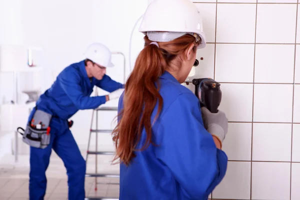 Female electrician using a power drill — Stock Photo, Image