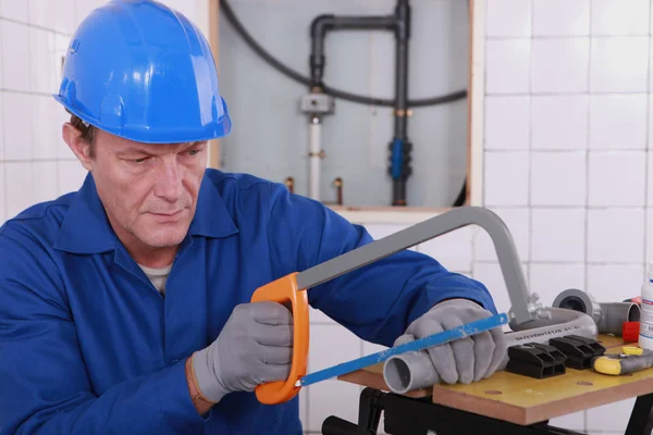 Plumber sawing plastic pipe — Stock Photo, Image
