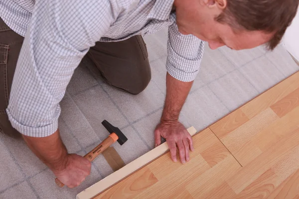 Чоловік ремонтує підлогу молотком — стокове фото