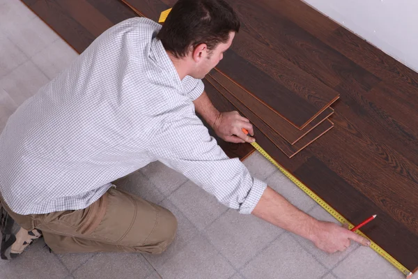 Homem medindo piso de madeira — Fotografia de Stock