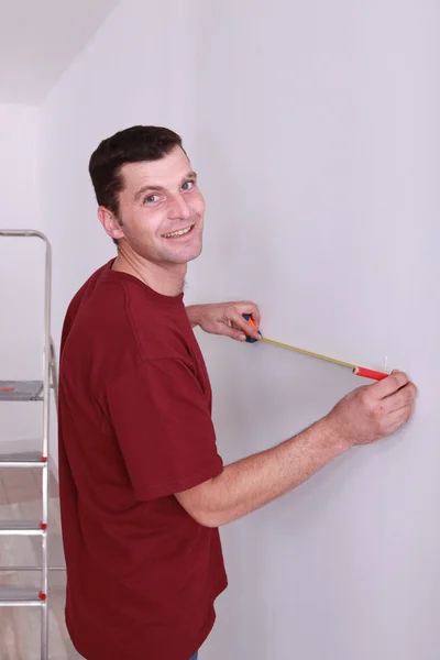 Человек измеряет стенку лентой — стоковое фото