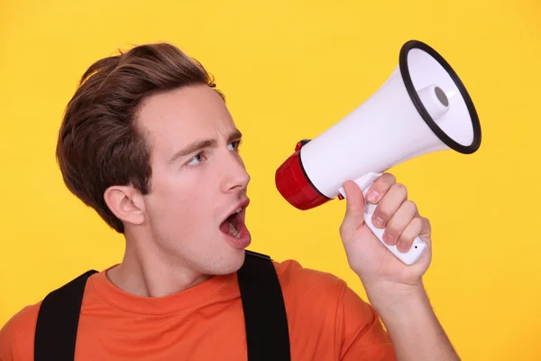 Young man hollering into a megaphone — Stock Photo, Image