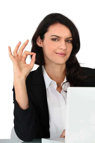 Ung affärskvinna med en bärbar dator att göra tecknet ok hand — Stockfoto