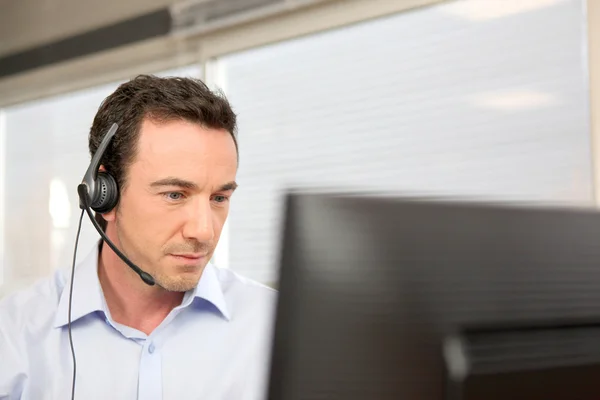 Man using a headset at a computer — Stock Photo, Image