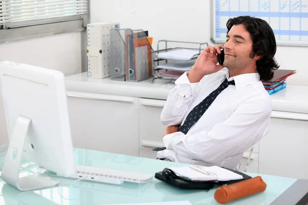 Бизнесмен пользуется телефоном за своим столом — стоковое фото